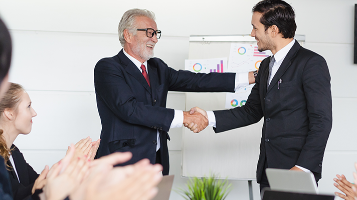 Young businessman promoted. Boss shaking hands with employee celebration for new position.1